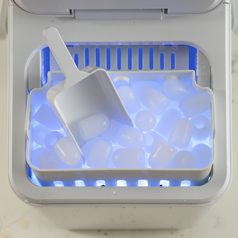 EdenPURE UV IcePRO ice maker with clear cylindrical ice cubes illuminated by blue LED light and white scoop inside tray