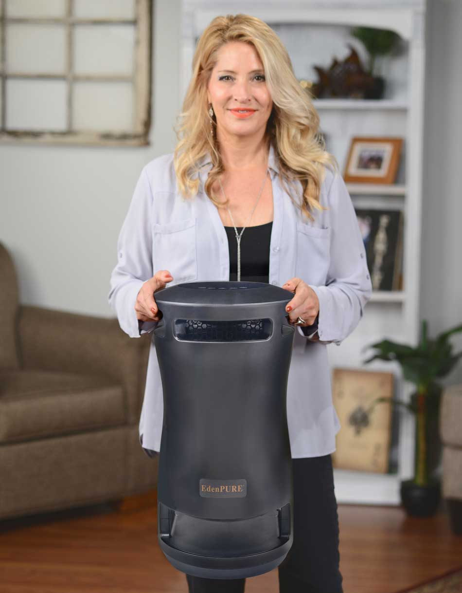 Woman holding black EdenPURE 360 Super Climater heater with curved design in living room setting
